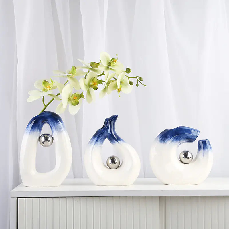 Set of three decorative vases with blue and white gradient on a white surface with a light gray curtain background.