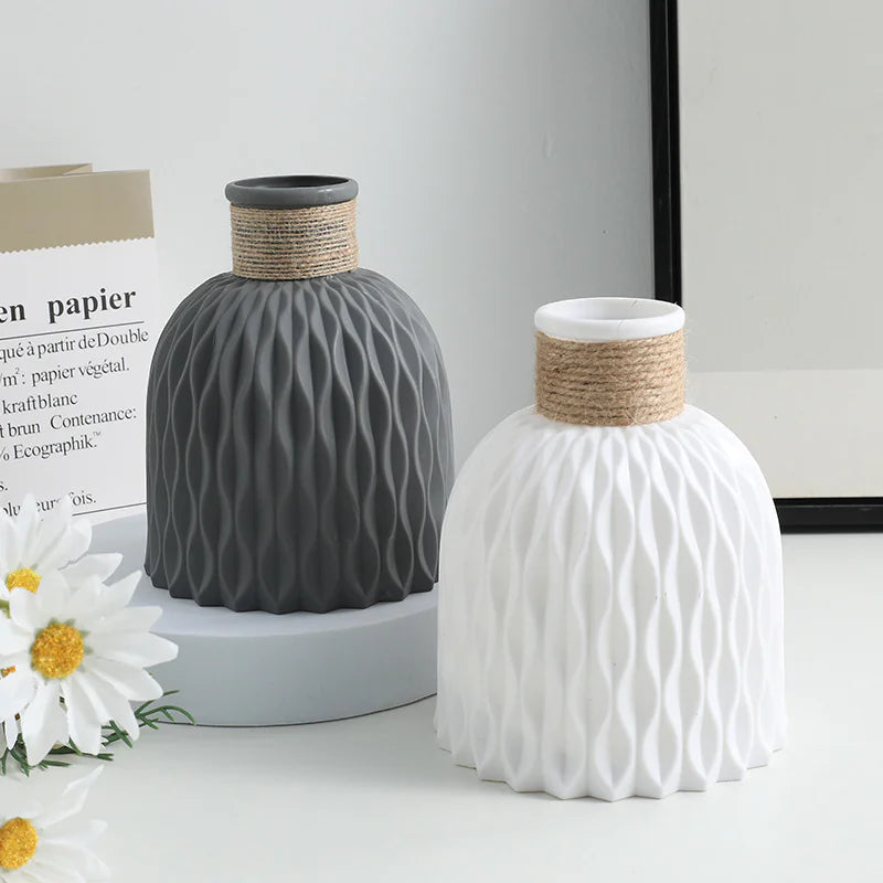 Two ceramic vases with textured design and woven accents on a light surface.