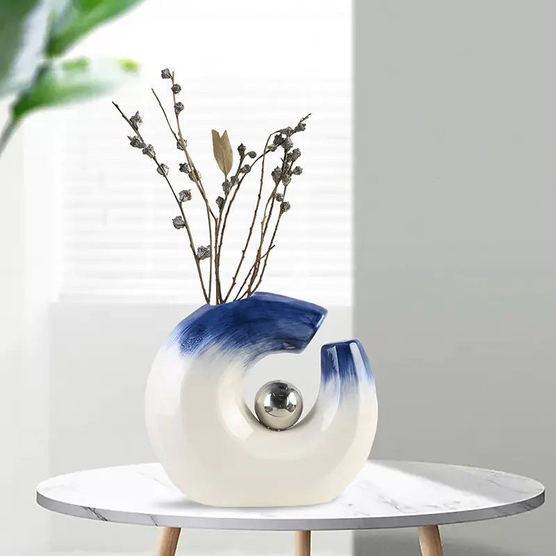 Decorative vase with blue and white gradient on a small round table against a light gray background