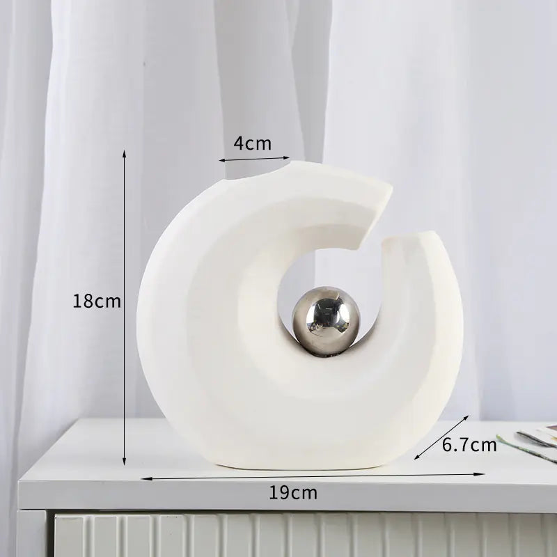 White decorative object with a silver ball on a white surface, measurements indicated.