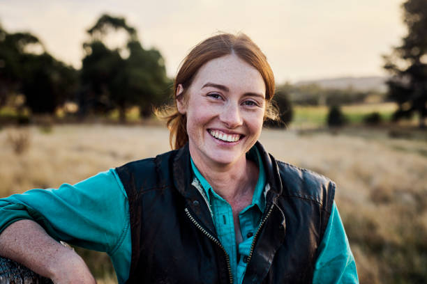 Woman smiling outdoors in a field with trees in the background