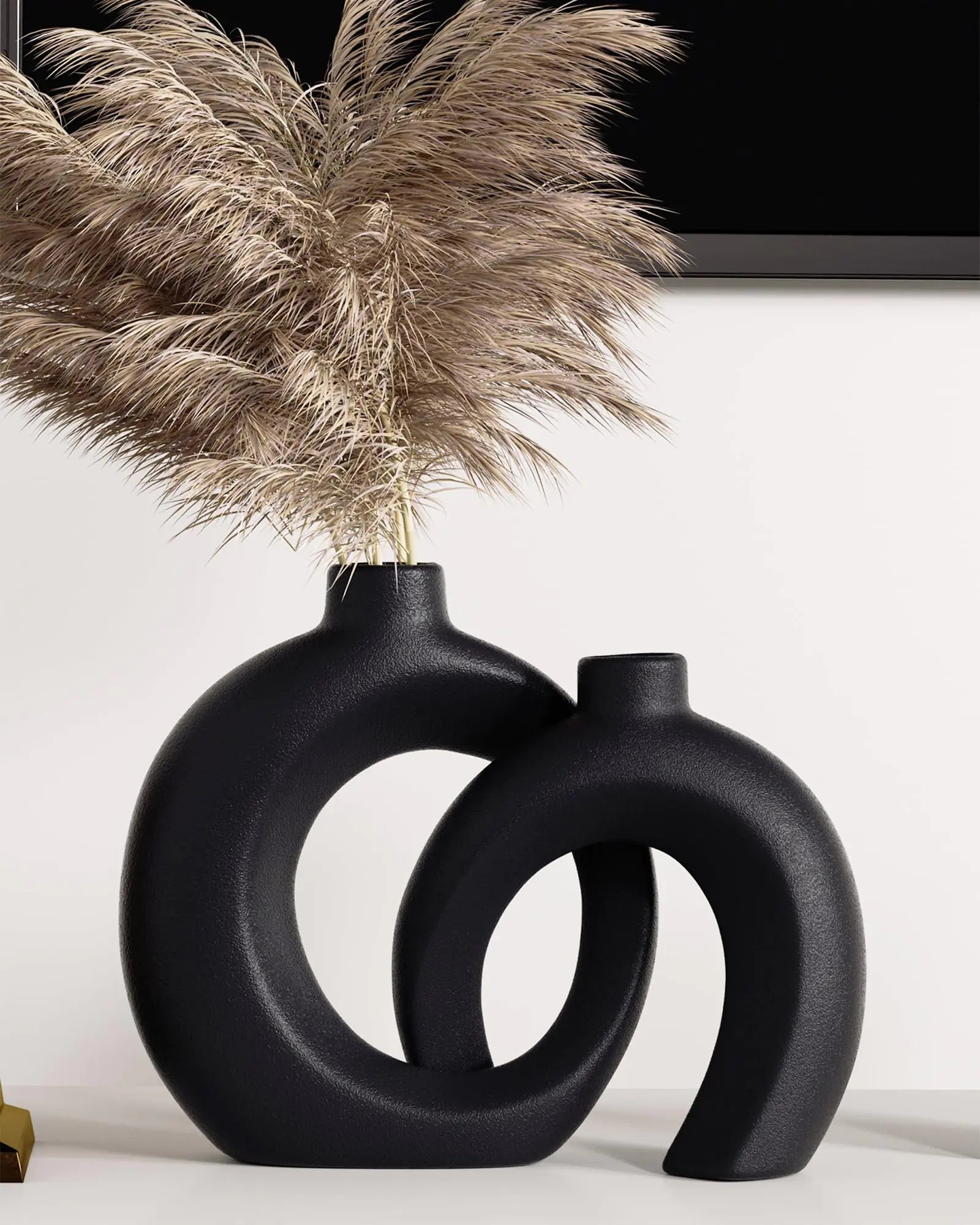 Black abstract vase with dried pampas grass against a white background