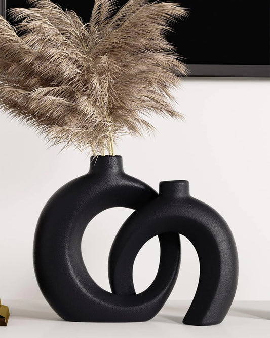 Black abstract vase with dried pampas grass against a white background