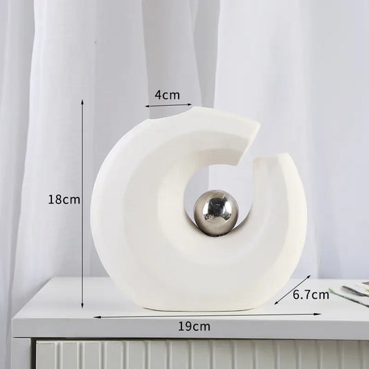 White decorative object with a silver ball on a white surface, measurements indicated.