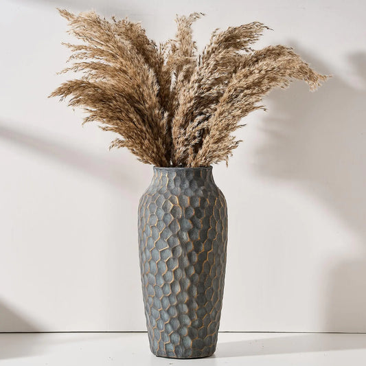 Textured vase with dried pampas grass against a white background